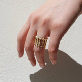 Gold ring on a finger against a light background