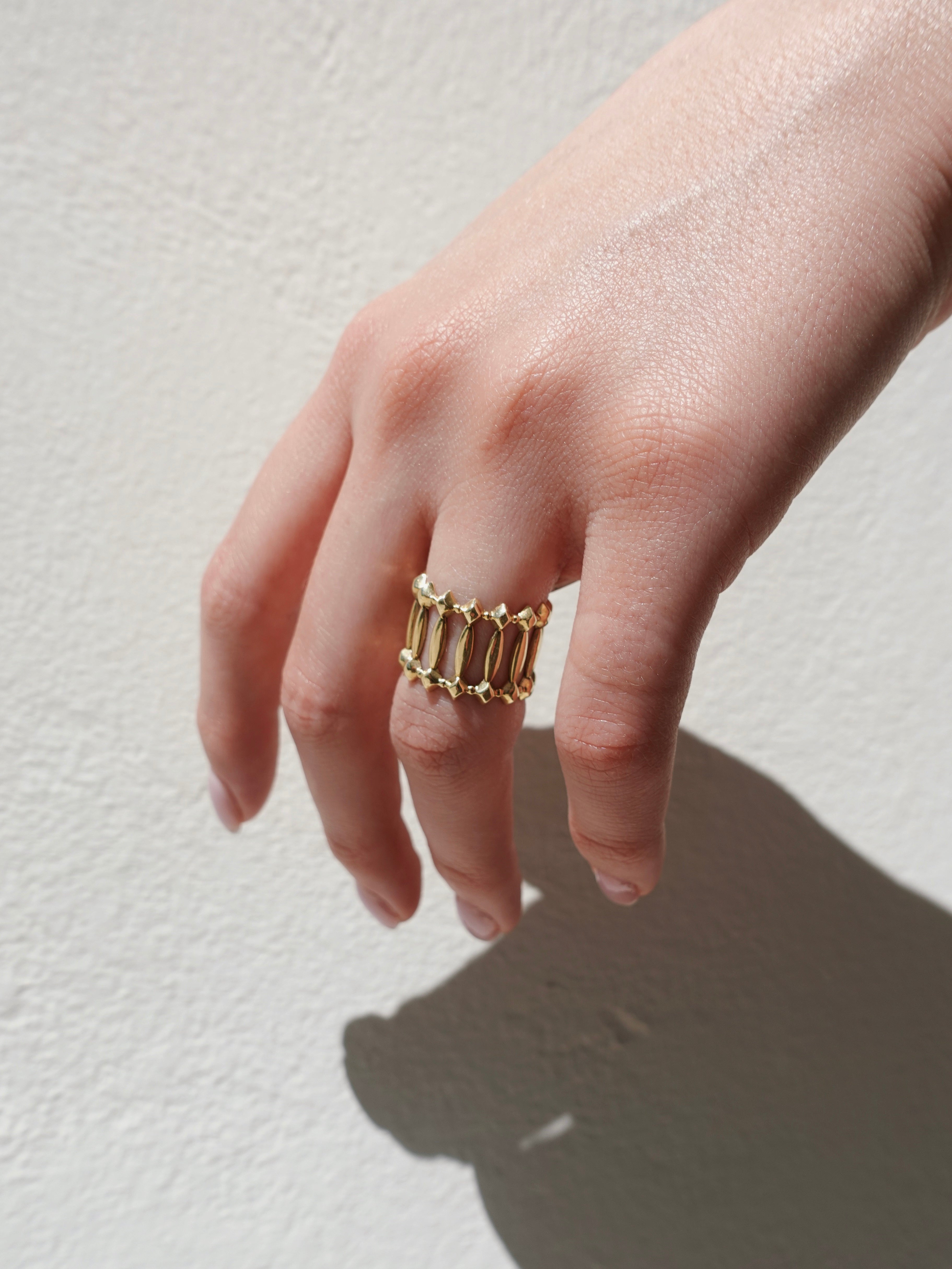 Gold ring on a finger against a light background