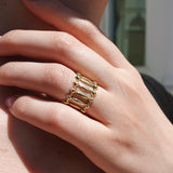 Hand wearing a gold ring, blurred background
