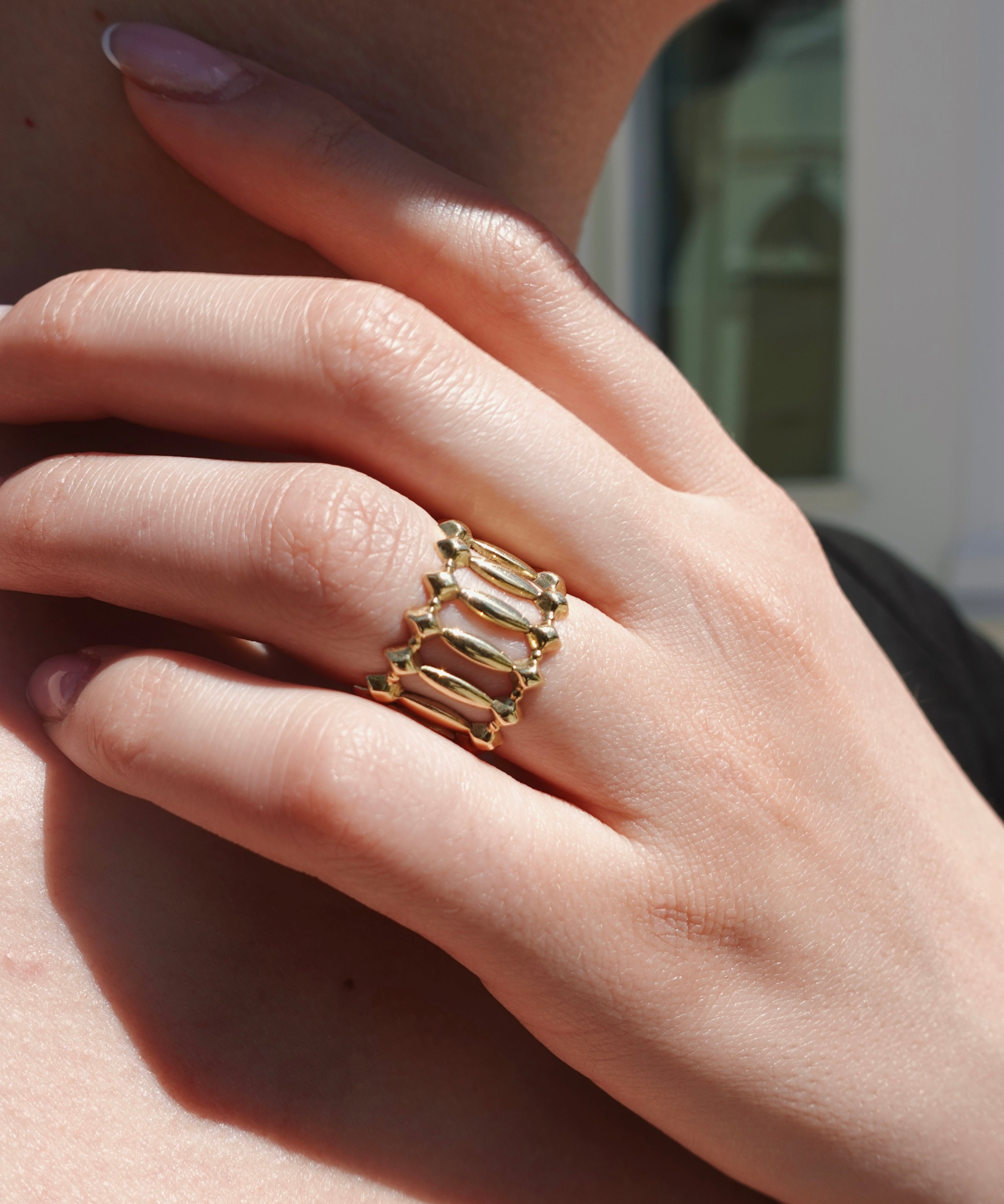 Hand wearing a gold ring, blurred background