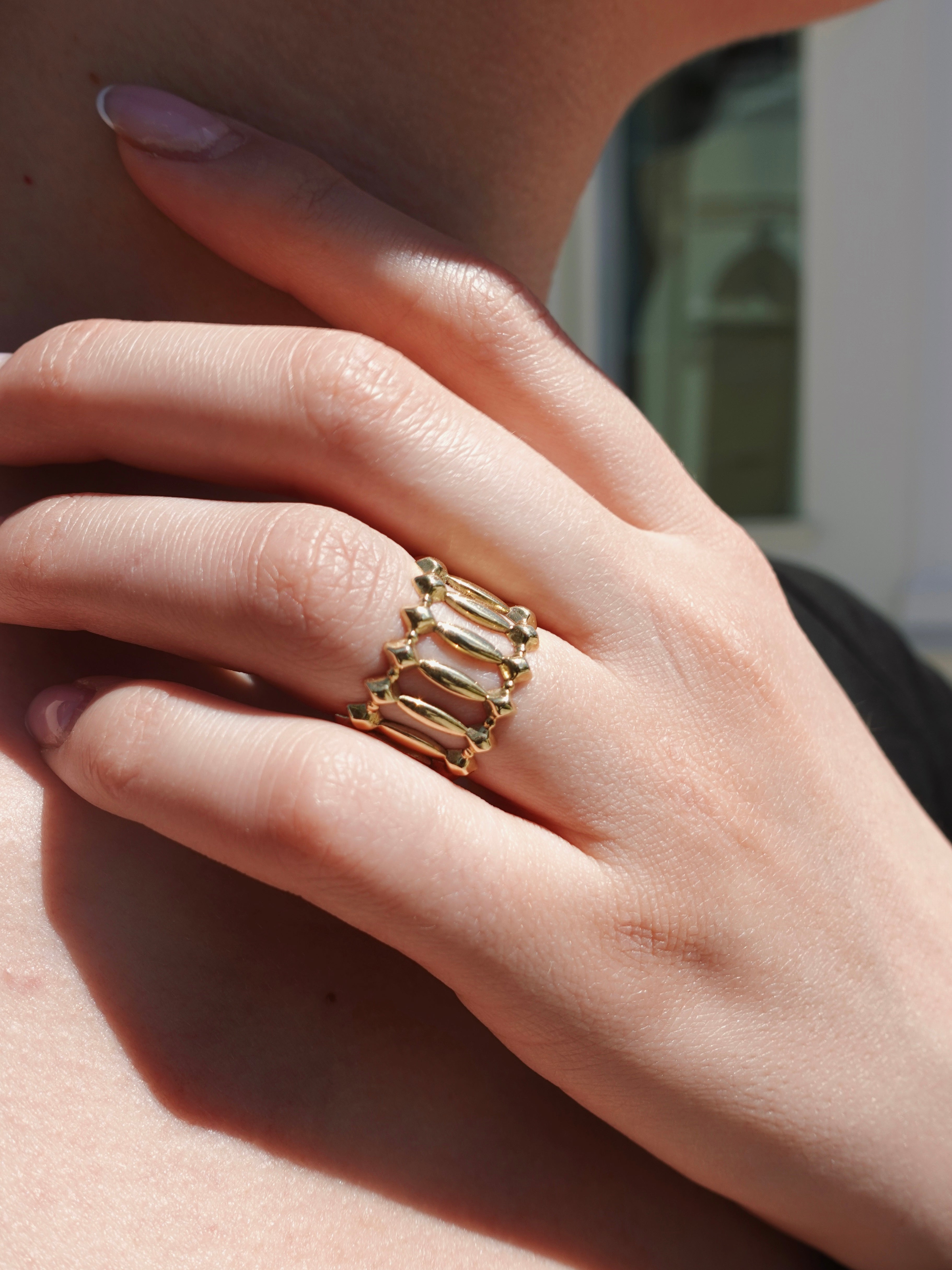 Hand wearing a gold ring, blurred background