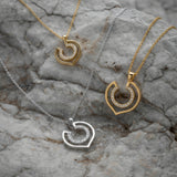Three geometric necklaces with diamonds over a textured stone surface