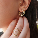 Gold hoop earrings being worn with a hand adjusting them.