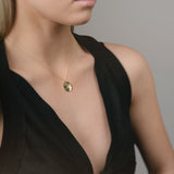 Woman wearing a black dress with a plunging neckline and a gold necklace.