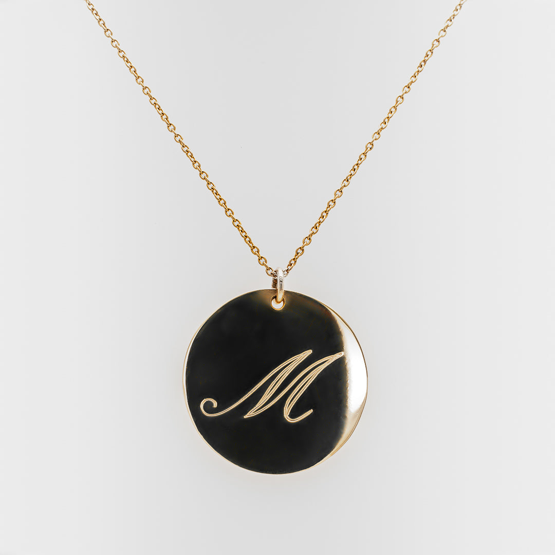 Necklace with a gold pendant featuring the letter 'M' on a white background