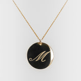 Necklace with a gold pendant featuring the letter 'M' on a white background