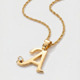 Gold necklace with a letter 'A' pendant on a light gray background