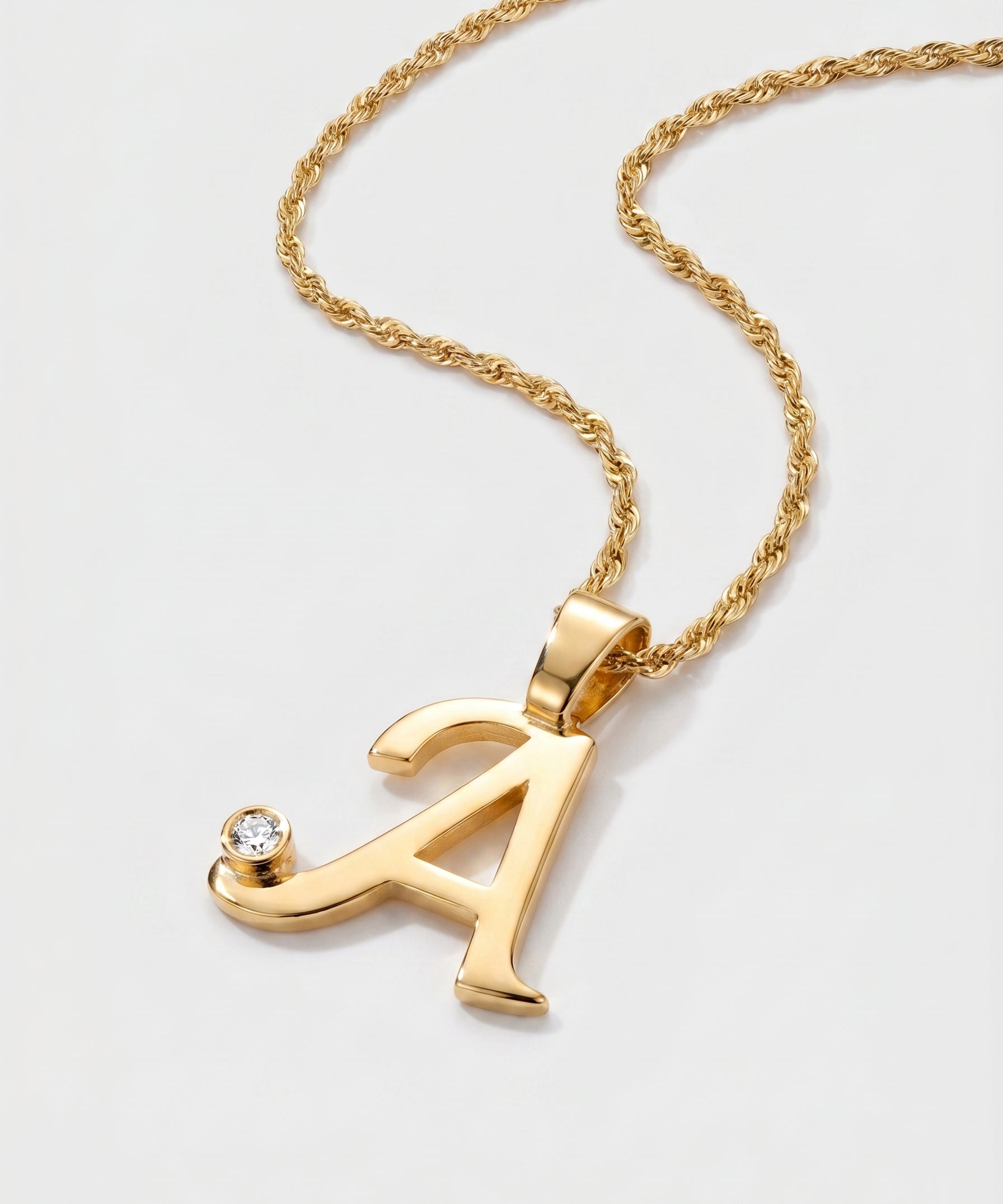 Gold necklace with a letter 'A' pendant on a light gray background