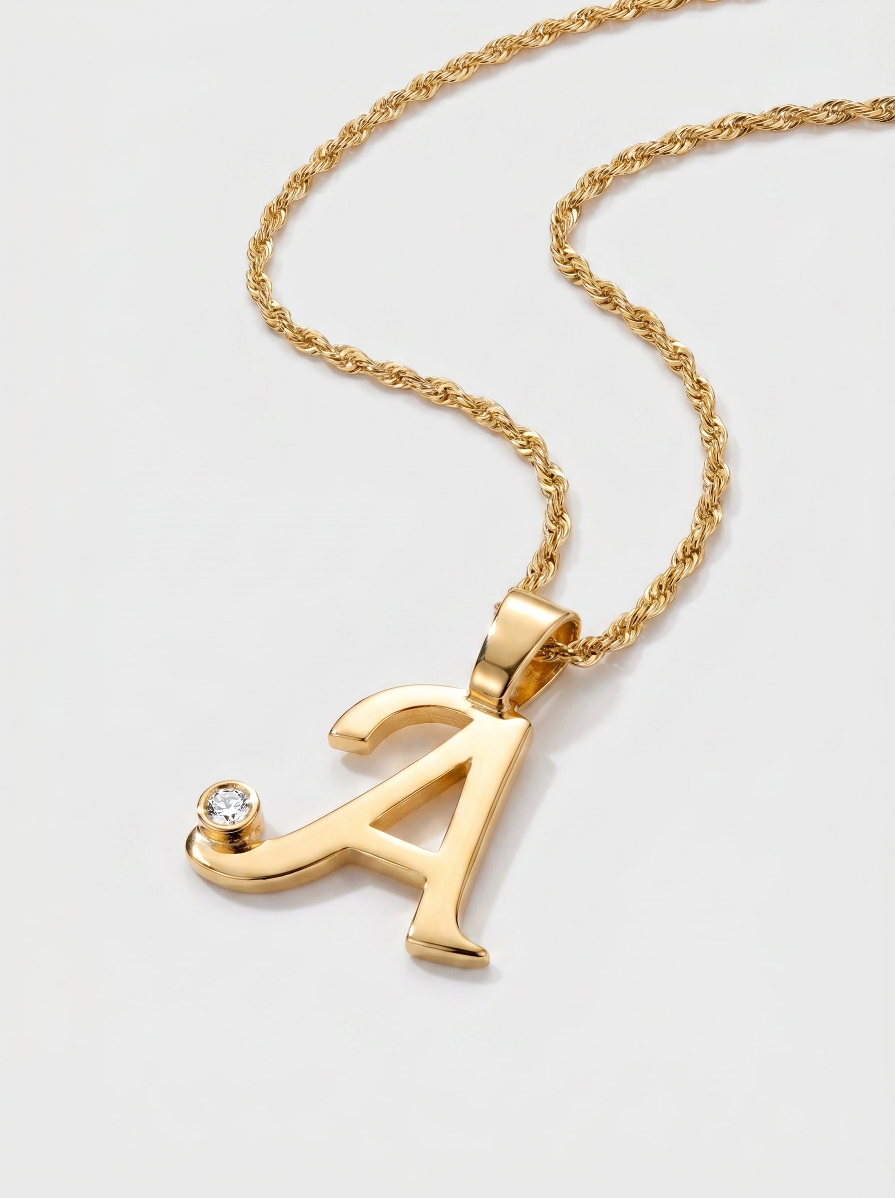 Gold necklace with a letter 'A' pendant on a light gray background