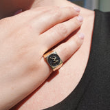 Close-up of a hand wearing a ring with a black diamonds and gold band.