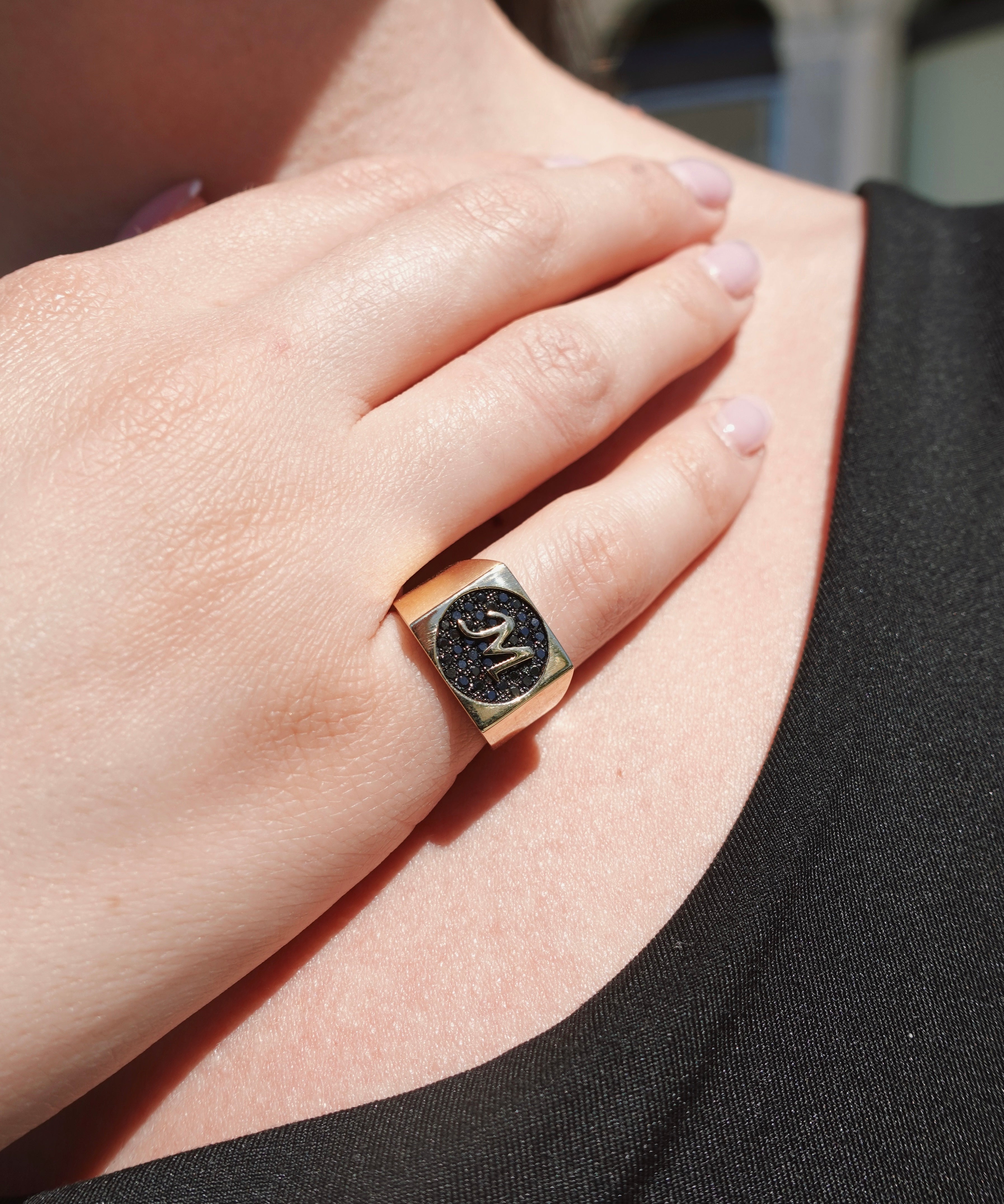 Close-up of a hand wearing a ring with a black diamonds and gold band.