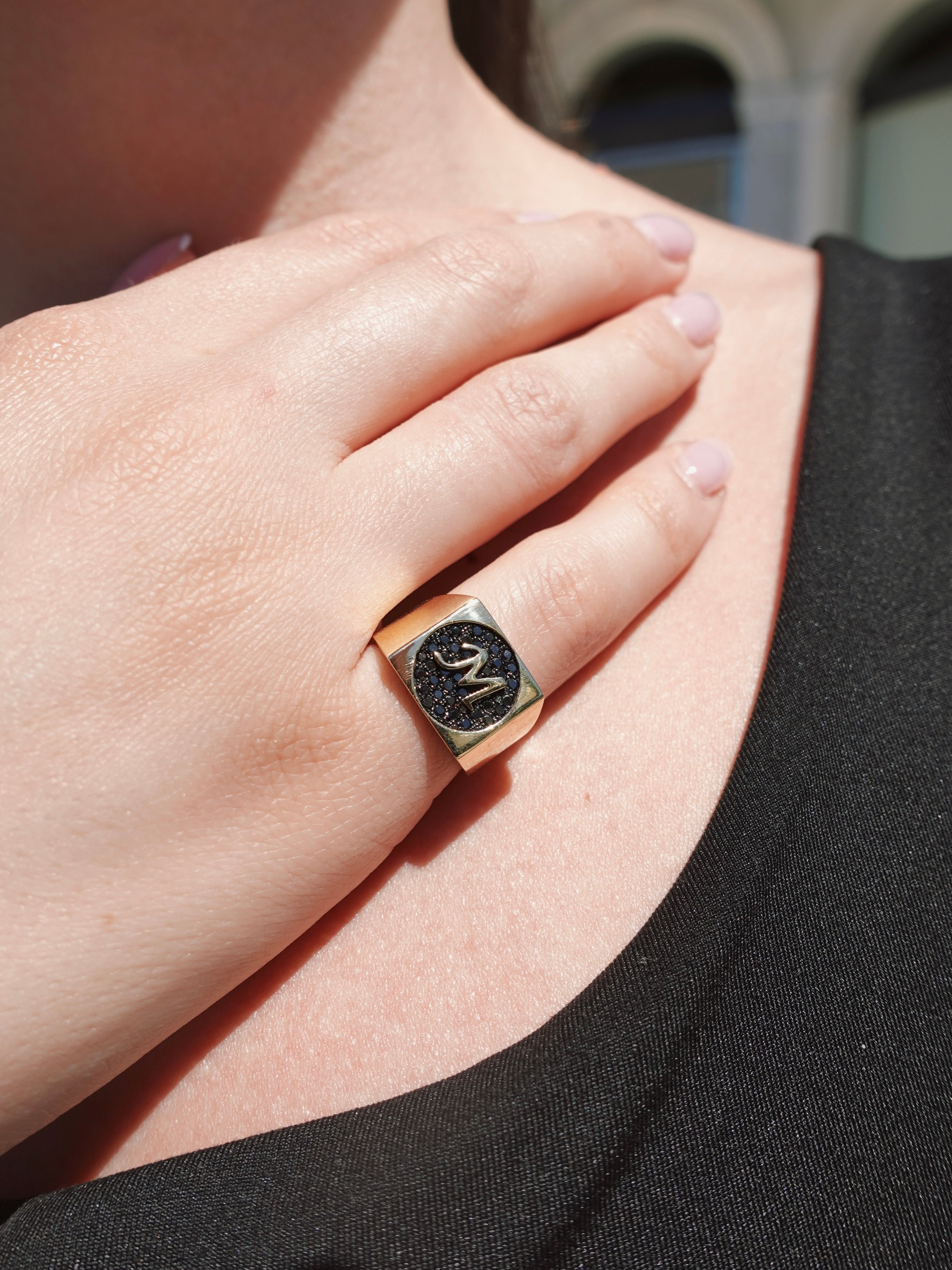 Close-up of a hand wearing a ring with a black diamonds and gold band.