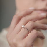 Close-up of a hand wearing a diamond ring with a blurred background