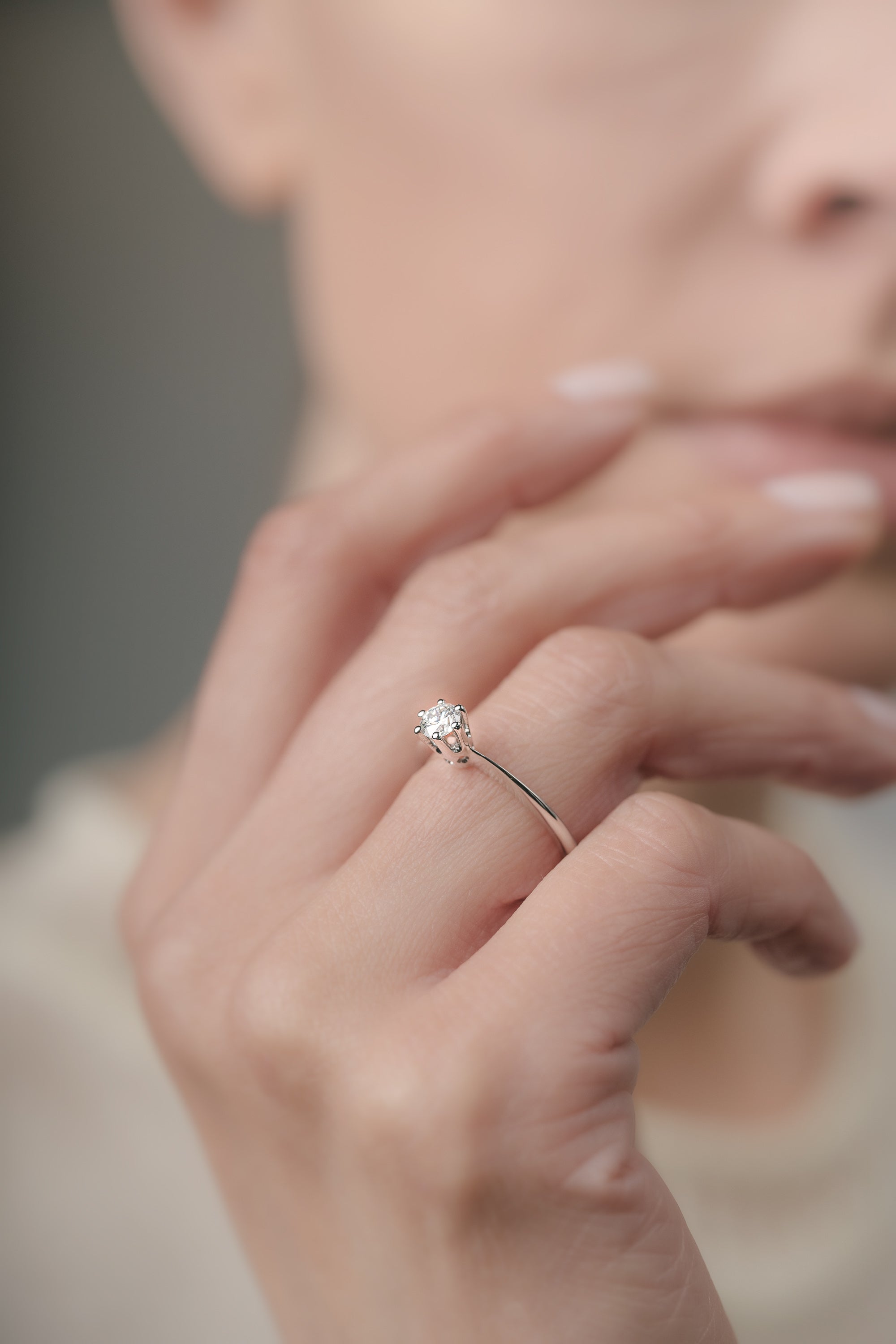 Close-up of a hand wearing a diamond ring with a blurred background