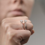 Close-up of a hand holding two diamond earrings against a blurred background