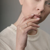 Woman wearing an engagement ring on her finger against a neutral background