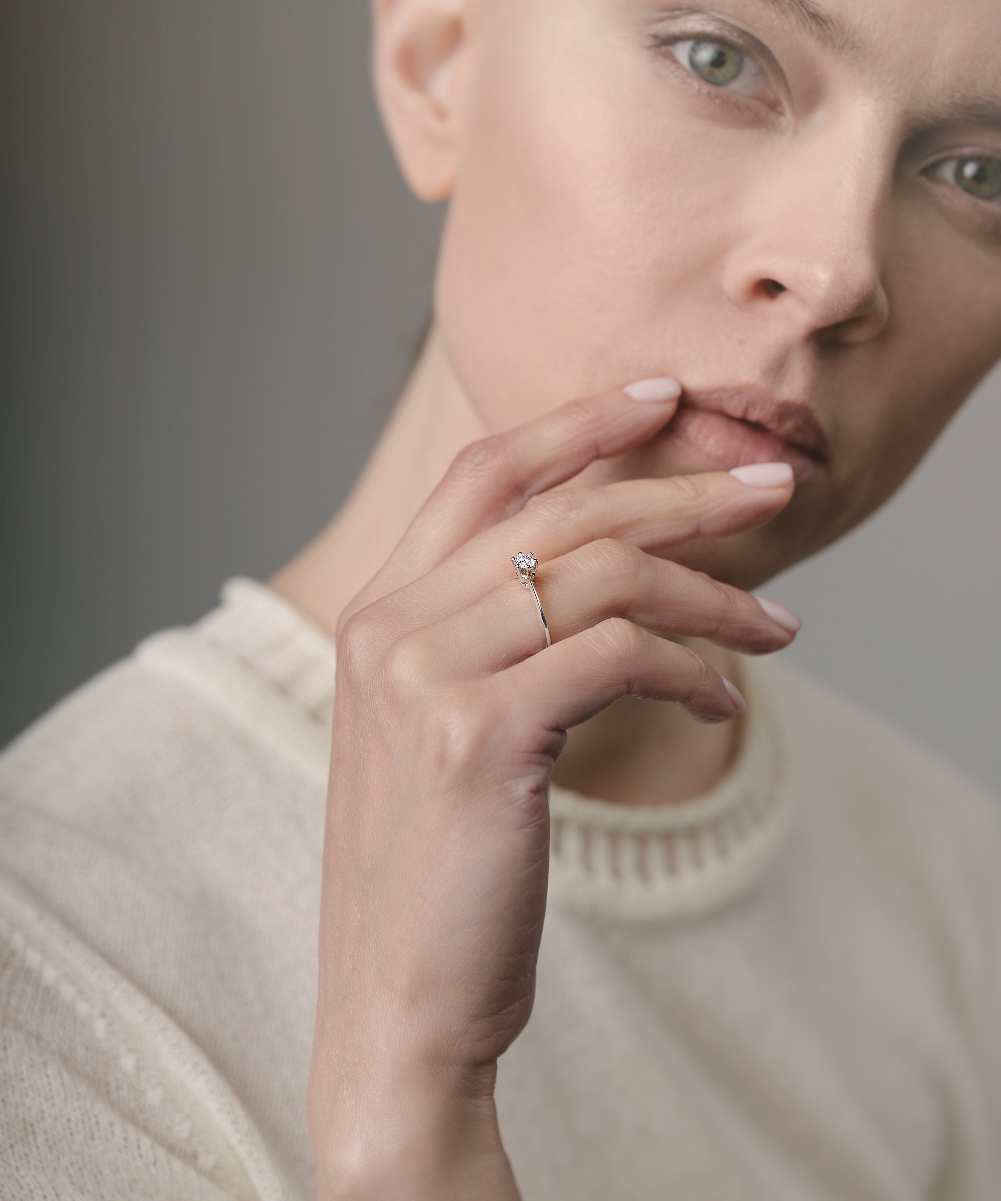 Woman wearing an engagement ring on her finger against a neutral background