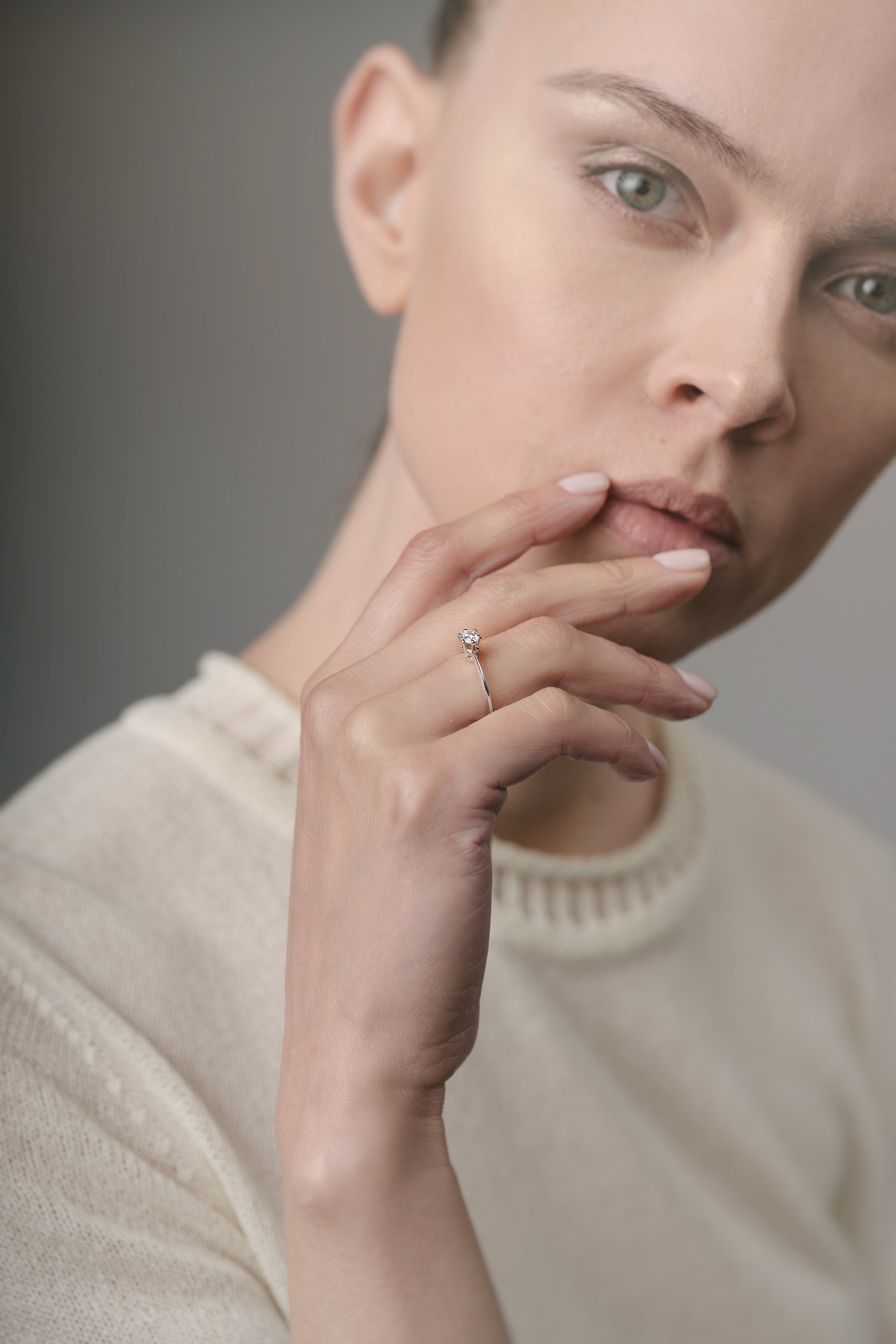 Woman wearing an engagement ring on her finger against a neutral background