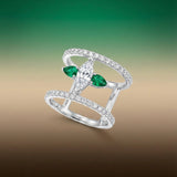 white gold ring with emeralds and diamond on a gradient background