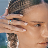 Close-up of a woman with braided hair wearing a special emerald ring and a blurred natural background