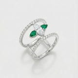 White gold ring with emerald and diamond accents on a light gray background