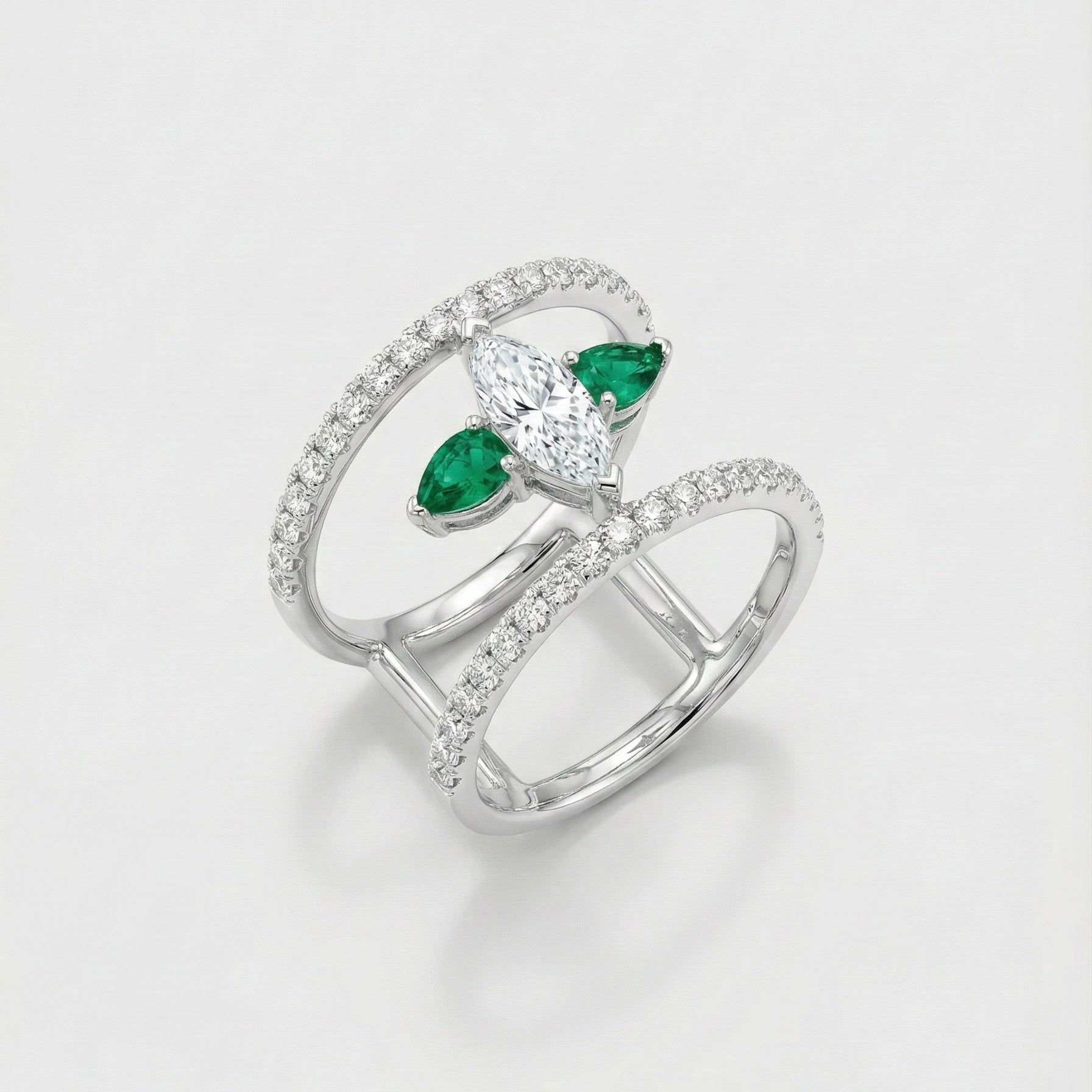 White gold ring with emerald and diamond accents on a light gray background
