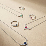 White gold jewelry set with gemstones and diamonds on a beige background
