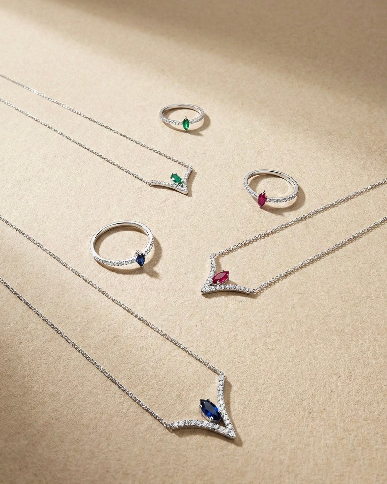 White gold jewelry set with gemstones and diamonds on a beige background