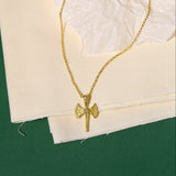 Gold necklace with a axe pendant on a textured white surface