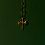 Gold cross pendant on a chain against a dark green background
