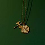 Gold necklace with two pendants on a dark green background