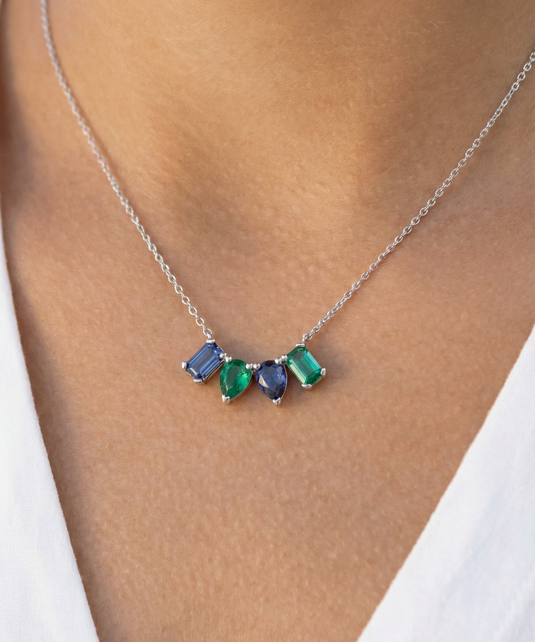 Necklace with green and blue mixed-shape gemstones worn by a person