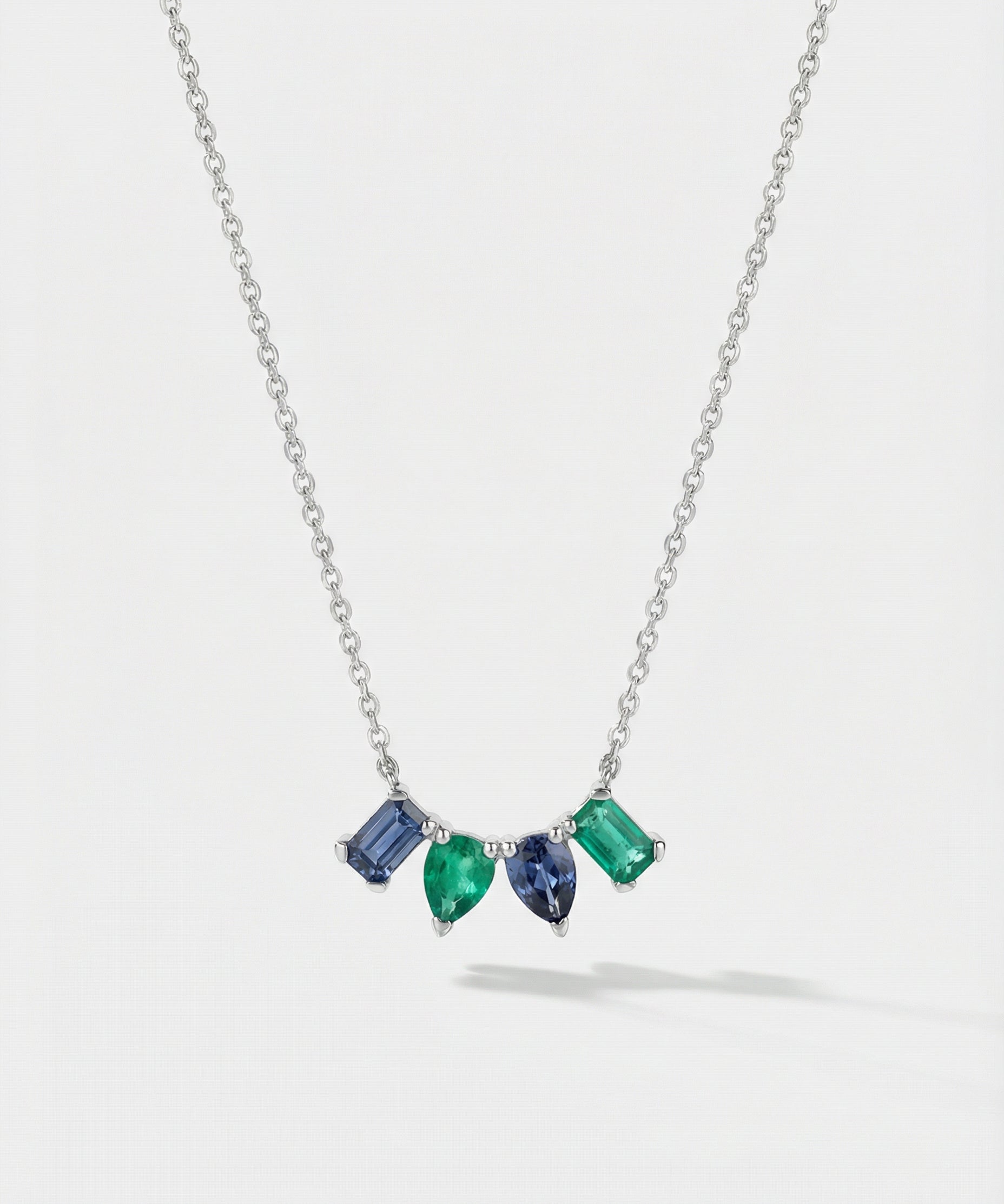 Necklace with four mixed-shaped gemstones on a light gray background