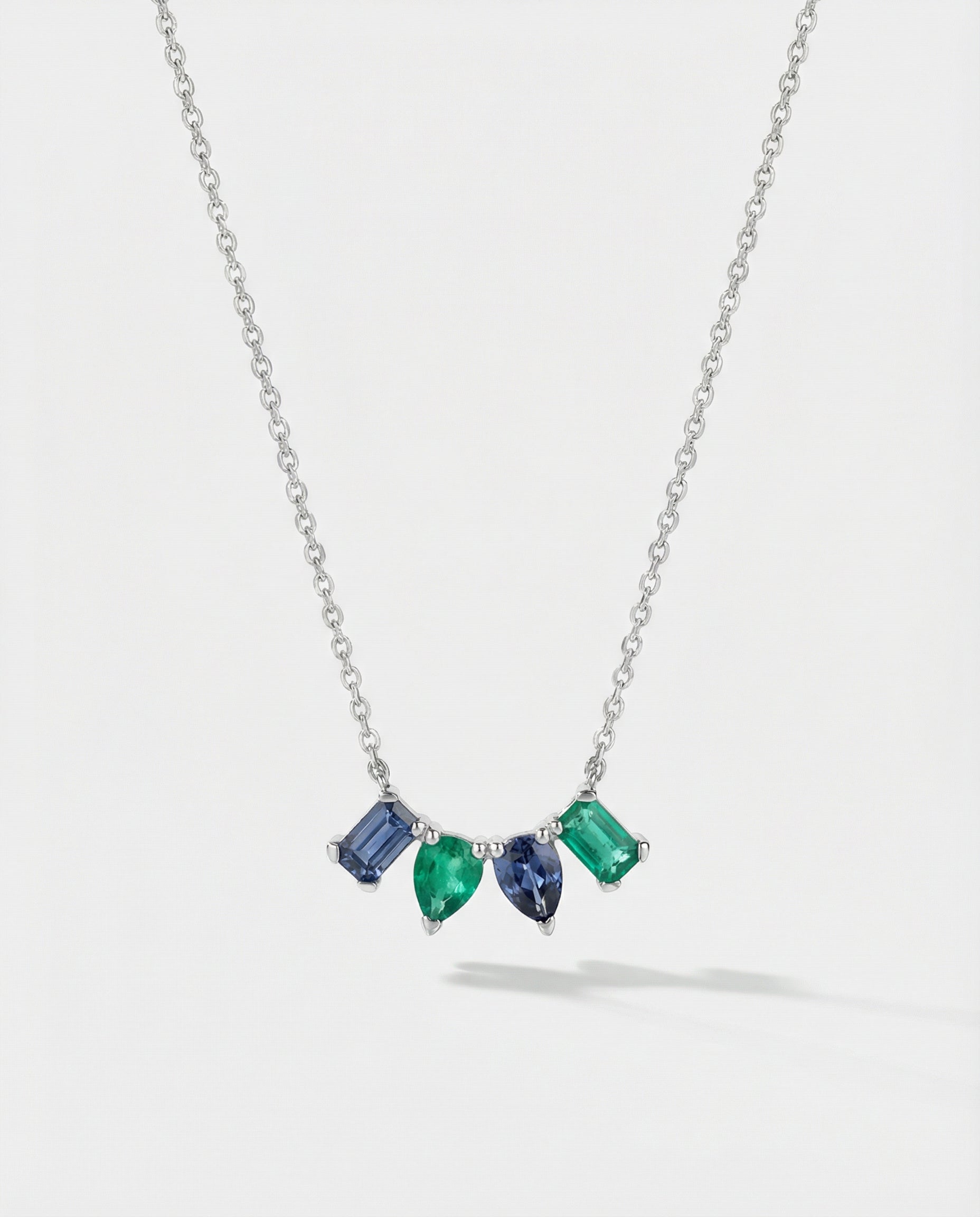 Necklace with four mixed-shaped gemstones on a light gray background