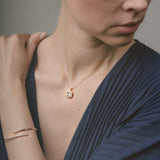 Woman wearing a gold necklace and bracelet against a neutral background