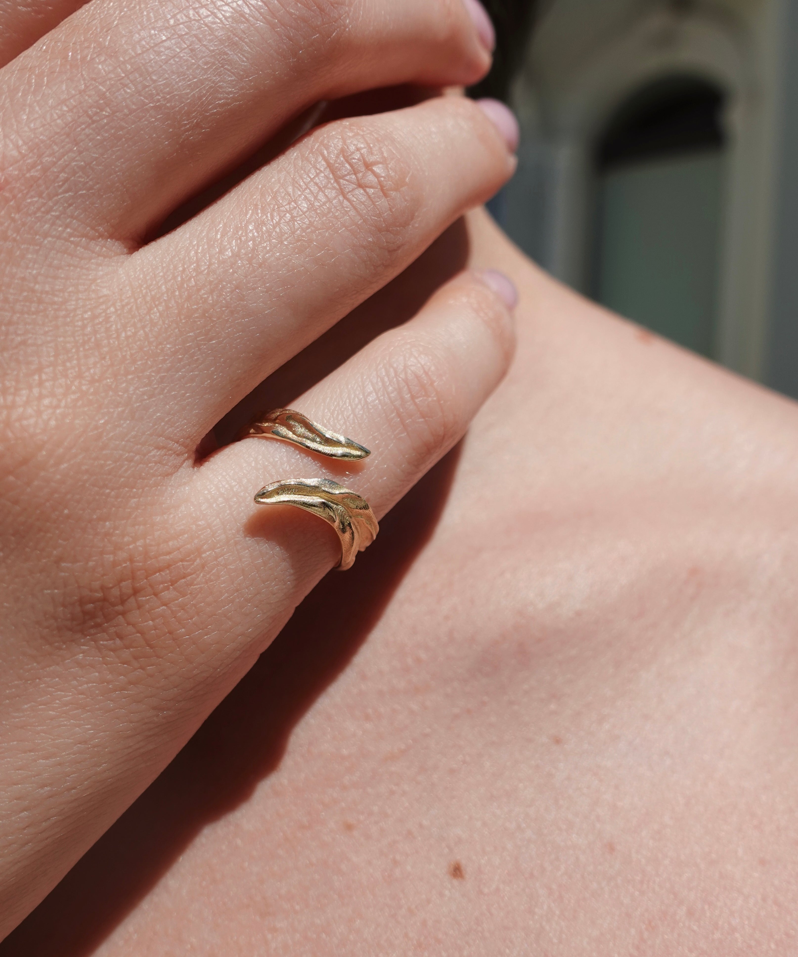 Close-up of a hand wearing gold ring on a blurred background