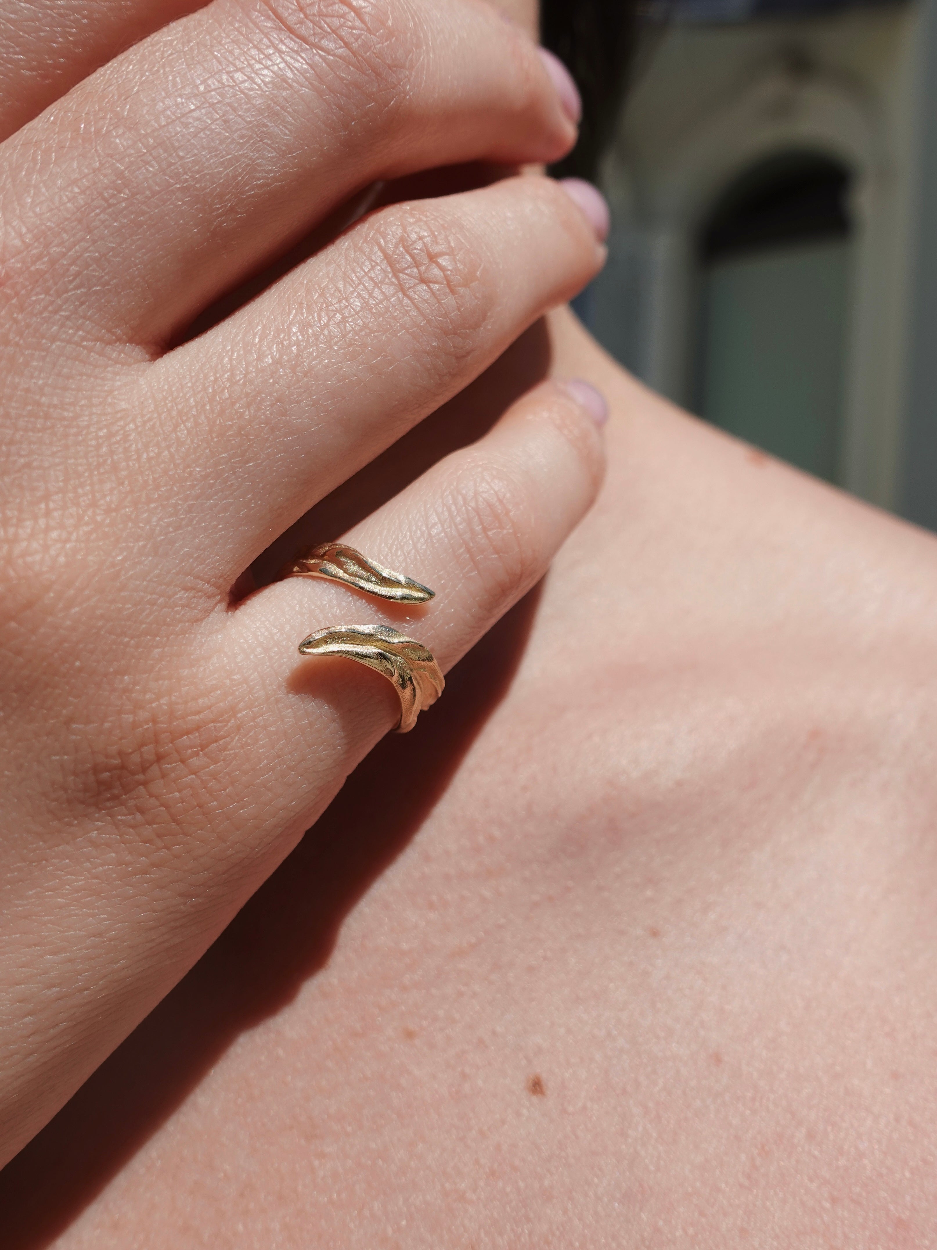 Close-up of a hand wearing gold ring on a blurred background
