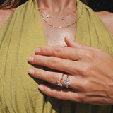 A close-up lifestyle shot of a woman wearing a delicate gold ring with a butterfly-shaped clear gemstone stack with another gold ring, paired with a green halter top.