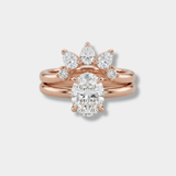 Rose gold wedding ring set featuring a central oval diamond solitaire ring with a matching three-stone sunburst cluster of pear, round, and marquise diamonds on a matching rose gold band, shown on a light gray background.