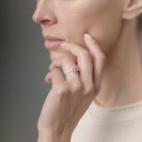 Woman wearing a ring on her finger against a neutral background