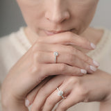 Close-up of a woman's hands with diamond rings on a neutral background