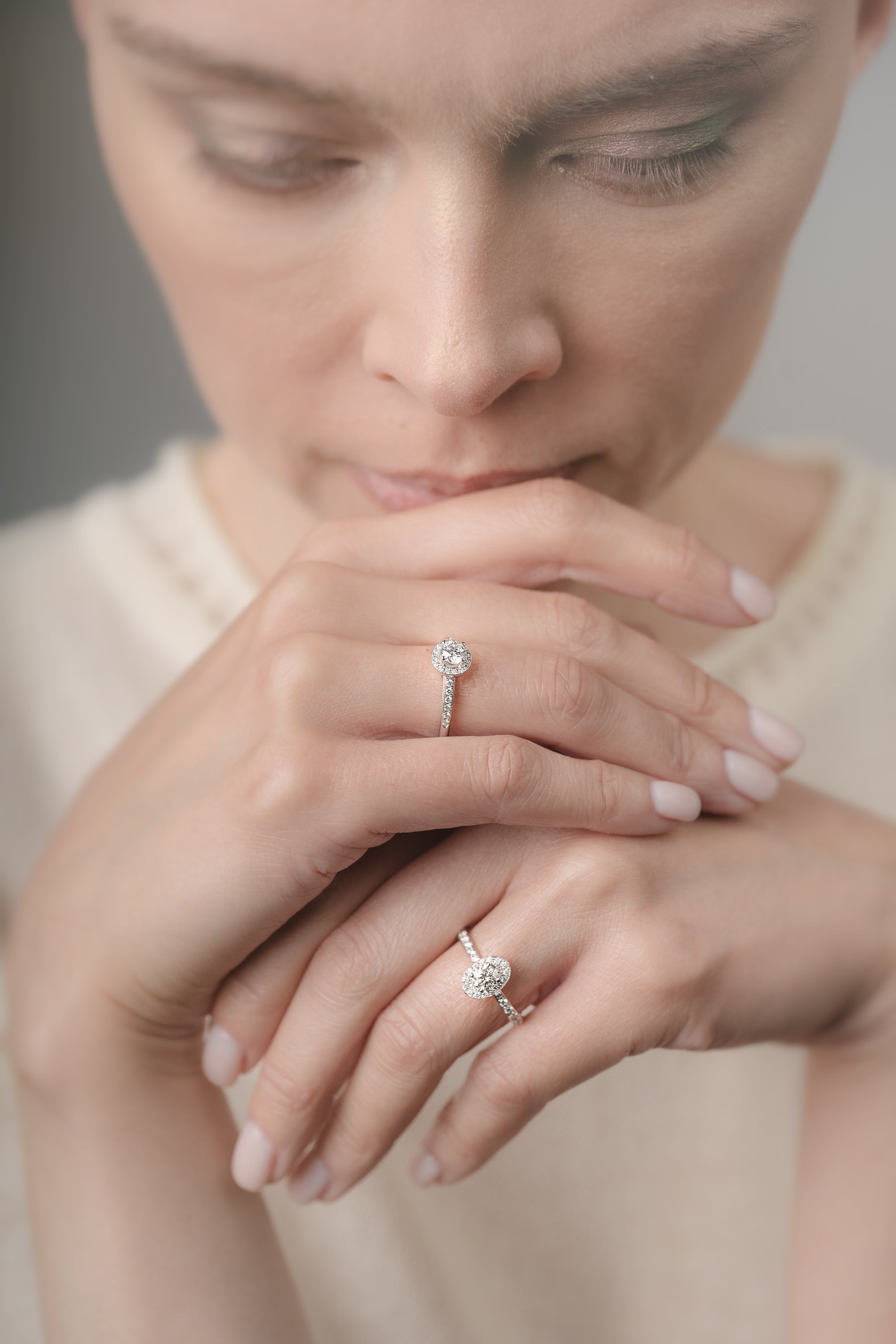 Close-up of a woman's hands with diamond rings on a neutral background