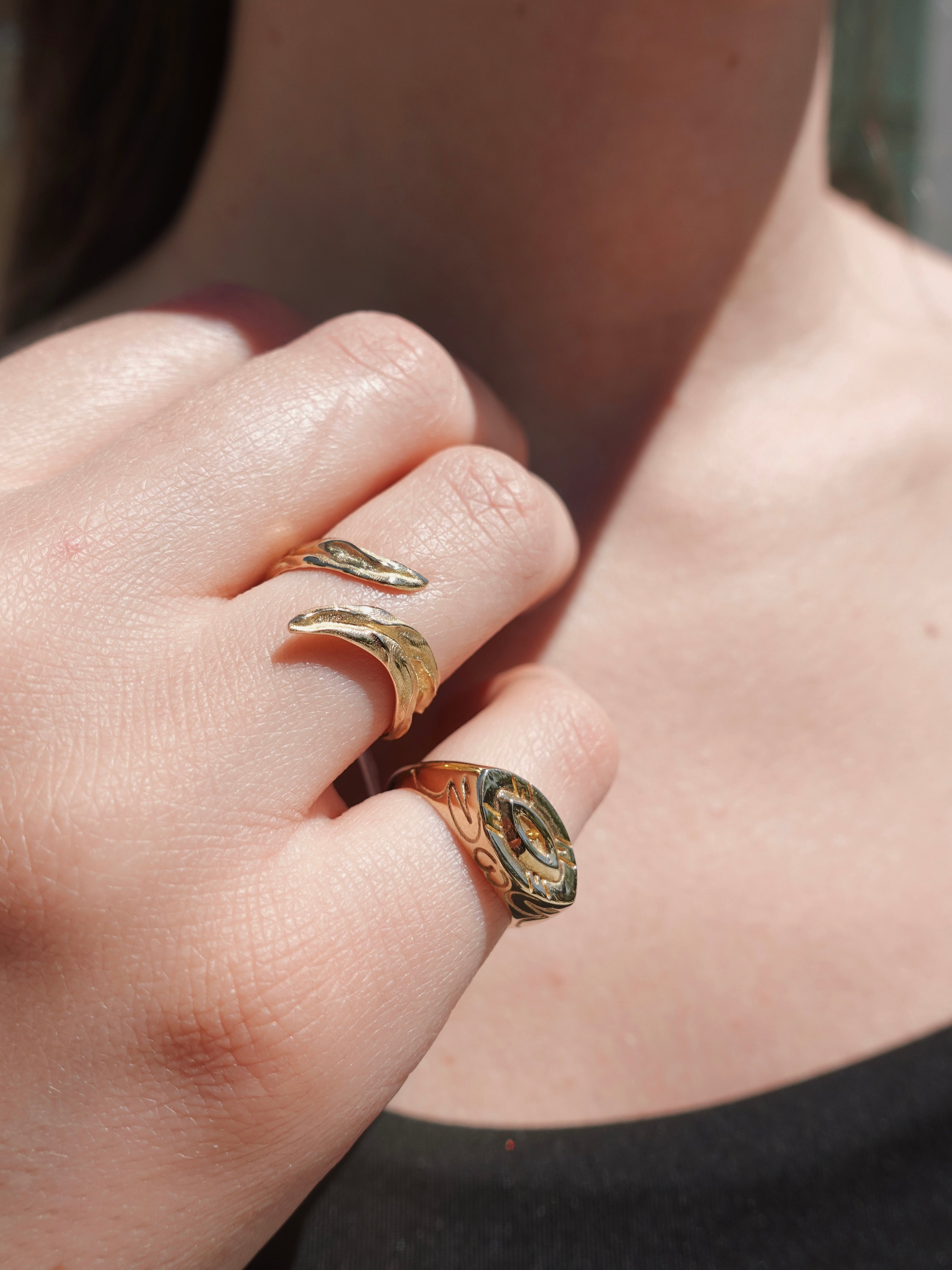 Close-up of a hand wearing two gold rings with special greek designs.