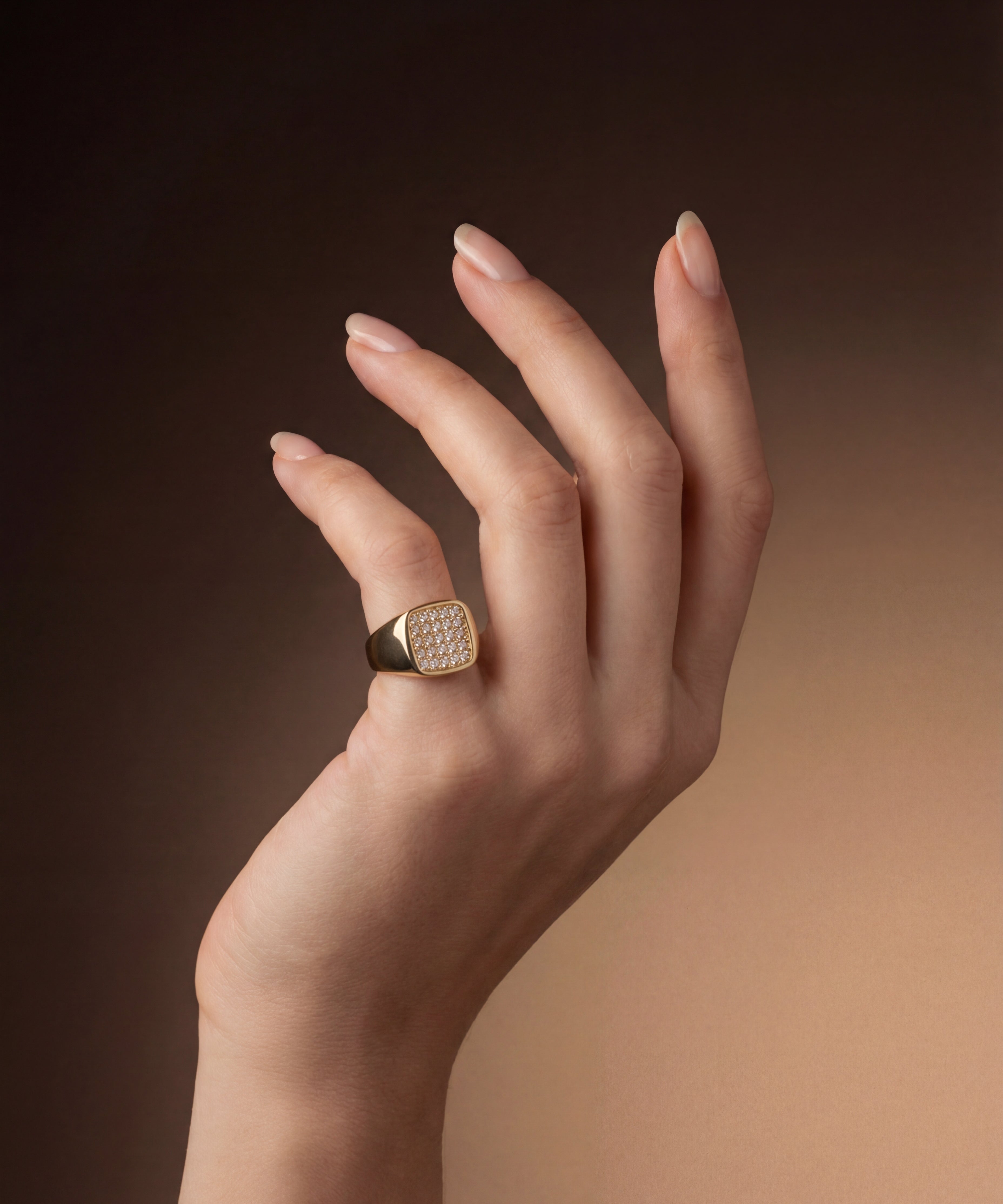 Hand wearing a gold ring with a diamond on a gradient brown background