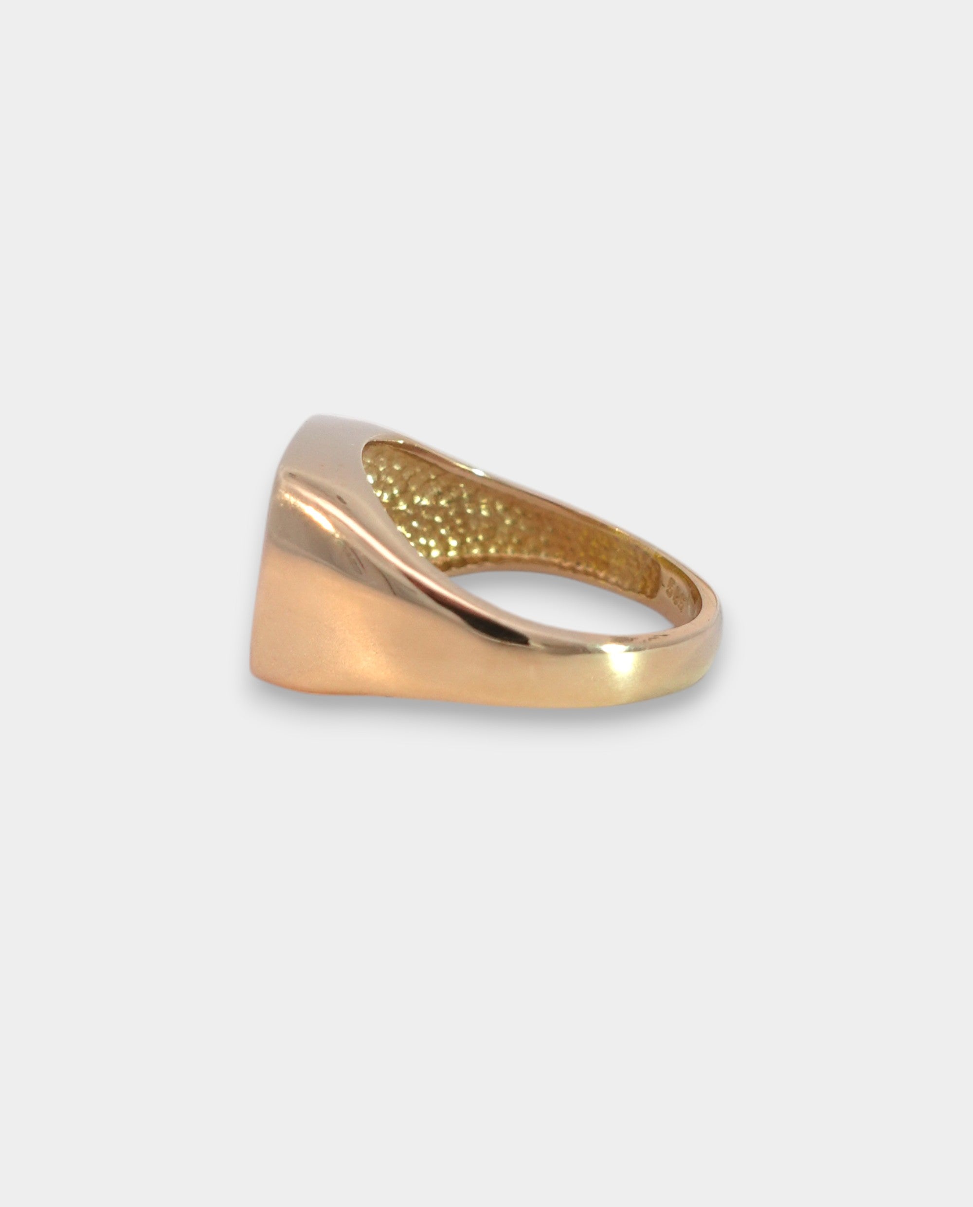 Gold ring with textured surface on a light gray background