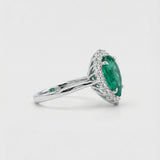 White gold ring with a green emerald gemstone on a white background