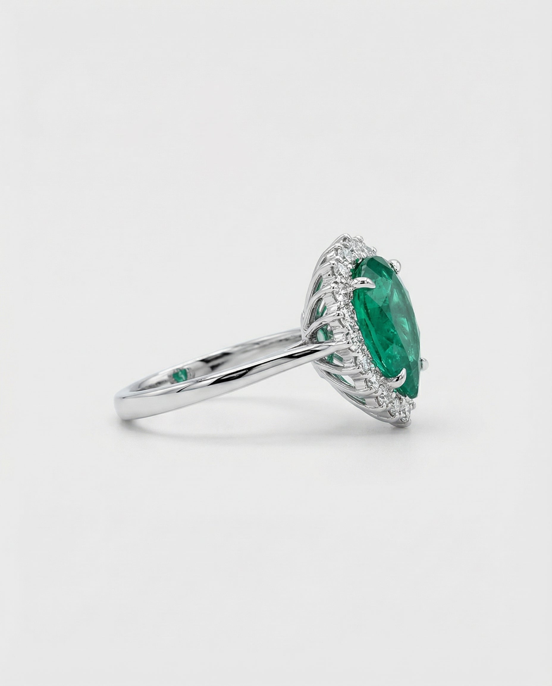 White gold ring with a green emerald gemstone on a white background