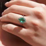 Close-up of a hand wearing an emerald ring with a blurred background