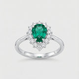 Ring with a green emerald gemstone and diamond accents on a light gray background