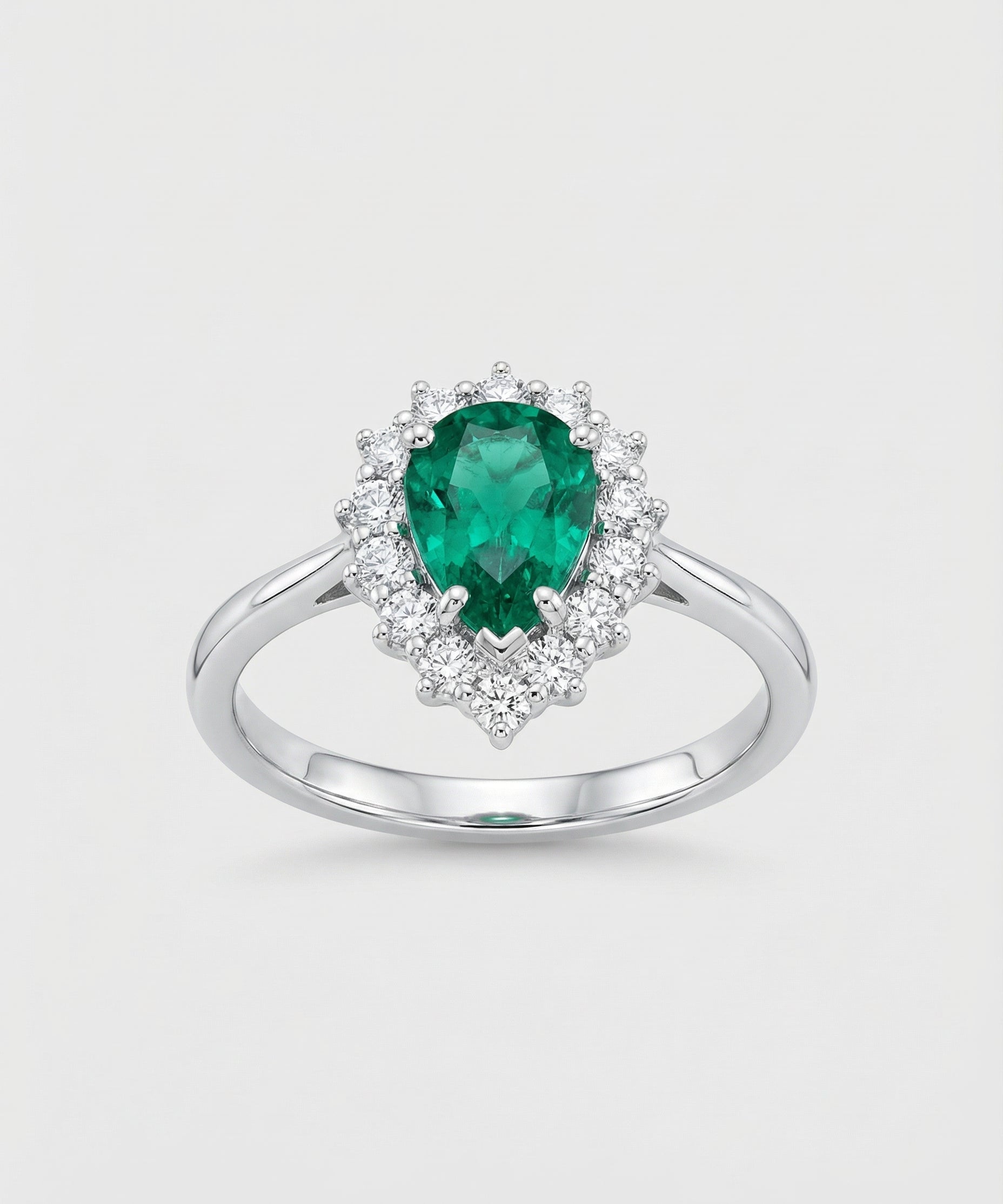Ring with a green emerald gemstone and diamond accents on a light gray background